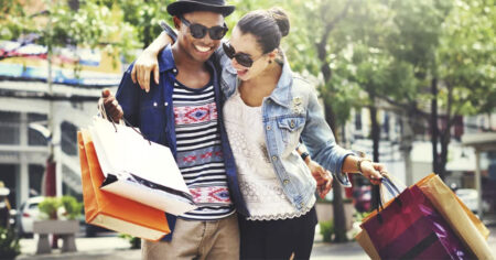 Un couple heureux fait du shopping en plein air, portant des sacs colorés et souriant