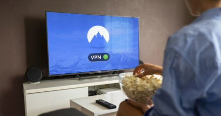 Une personne regarde la télévision avec un écran affichant un VPN activé, tout en mangeant du pop-corn